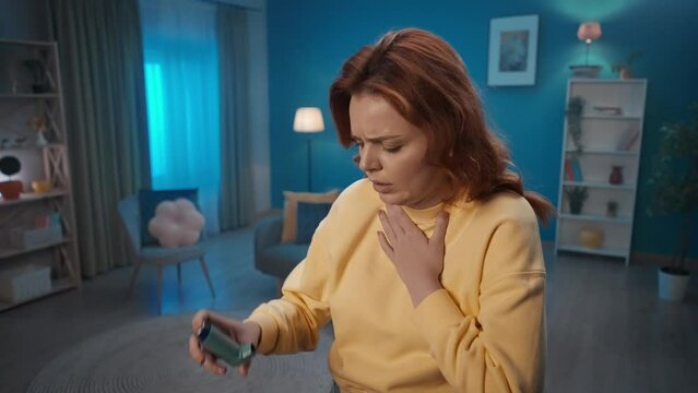 A woman uses an asthma inhaler during a coughing fit close up. A woman using an inhaler begins to breathe normally. Home medicine concept.
