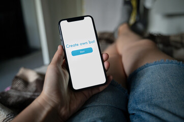 Person laying down on couch and creating own chat bot on smartphone