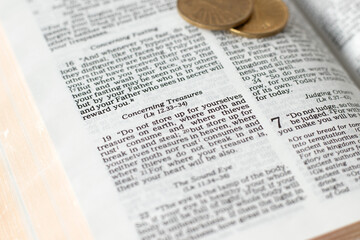 Obraz premium Biblical verses concerning treasures in open holy bible with golden coins. Christian teaching for serving God versus money, biblical concept. Selective focus.
