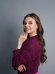 Obraz premium Portrait of a beautiful young woman in a purple sweater on a gray background