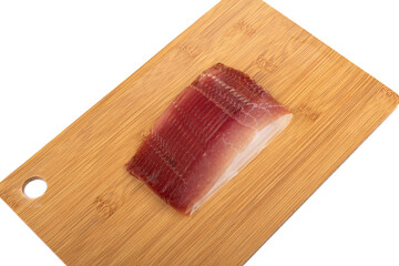 Slicing delicious jamon on a cutting board on a white background.