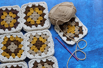 Close up photo of crocheted square motives made of soft wool. Retro style blanket in making. Crochet pattern texture. 