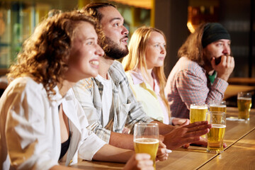 Sport fans, friends sitting at pub, bar, watching online football match translation, drinking beer, cheering up team. Concept of sport competition, hobby, lifestyle, human emotions, fun