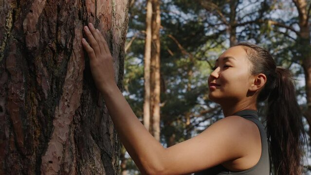 Young Asian woman meditating near a tree in the forest