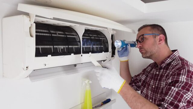 Service guy cleaning and maintaining air condition unit.