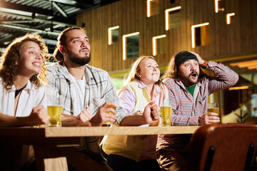 Emotive sport fans, friends, men and women sitting in cafe and watching football match translation, cheering up favourite team. Concept of sport competition, hobby, lifestyle, human emotions, fun