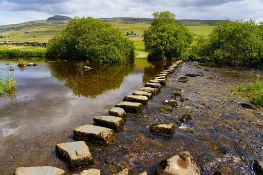 Beautiful view across the River Doe stepping stones with The Ingleborough mountain in the distance, which is at the halfway point along the Ingleton waterfalls trail, Ingleton, North Yorkshire, UK.