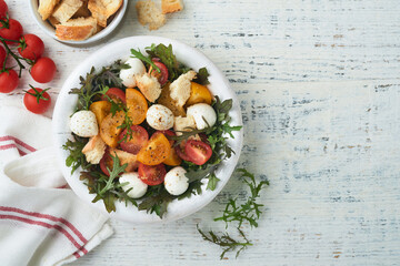 Tuscan Panzanella. Cherry Tomatoes salad with arugula, basil, mozzarella and bread crackers on white bowl. Traditional italian salad. Mediterranean healthy food and cuisine.