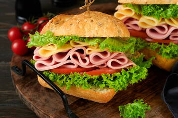 Sandwich. Tasty sandwich with ham or bacon, cheese, tomatoes, lettuce and grain bread on dark backgrounds. Delicious club sandwich or school lunch, breakfast or snack.
