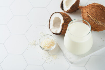 Glass of coconut milk and coconut close up on a white background with space for text. Coconut vegan milk non dairy or Dairy free milk concept. Healthy vegan food.