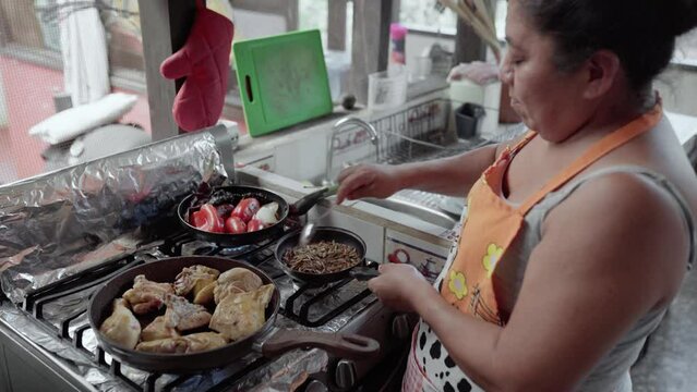 Una mujer Hispana adulta est&aacute; calentando s&eacute;samo y pipas para preparar mole