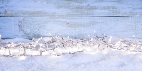 Christmas winter background with fairy lights in snow in front of blue wooden wall - New Year xmas...