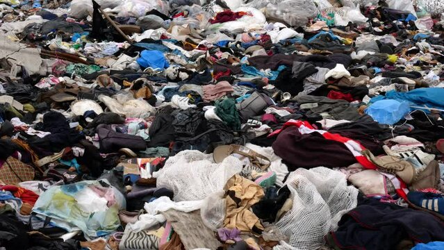 Video footage of a textile dump outdoors. Problems with an overabundance of unsold products.