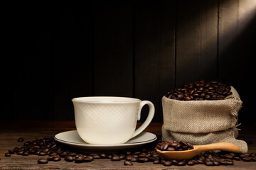 Fototapeta premium white coffee cup with black coffee or hot tea in a cappuccino espresso cup Breakfast with coffee beans on wooden table isolated on black background