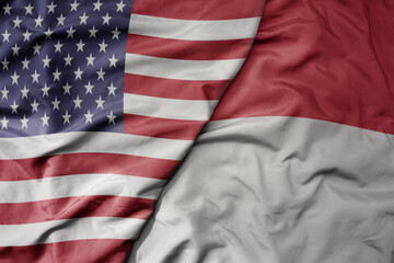 big waving colorful flag of united states of america and national flag of indonesia .