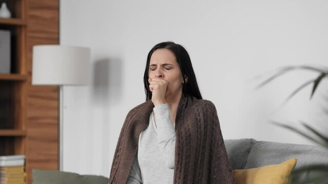 Portrait of ill young woman at home having cough and sore throat. First symptoms of cold and flu virus, pneumonia, bronchitis and respiratory tract infection. Seasonal virus disease.