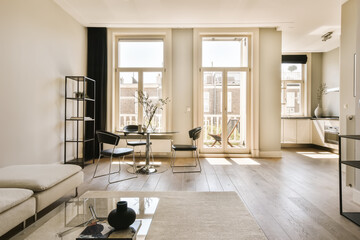 a living room with white walls and wood flooring in the center of the room, there is a large window that looks out onto