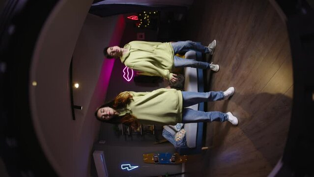 Girl with boy Gen Z Asian bloggers record trending reels for followers. Dance hip hop style recording video on phone camera with ring led lamp. Trending dance reel tiktok instagram youtuber vertical