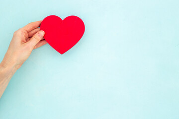 Obraz premium Woman holding red heart in hands. Medical insurance or health care concept