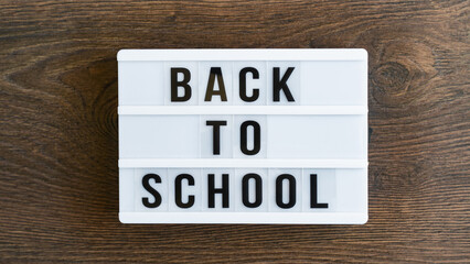 Back to school concept. School supplies on wooden background. Back to school lettering on white letter board. Copy space for text. Selective focus included
