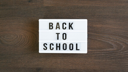 Back to school concept. School supplies on wooden background. Back to school lettering on white letter board. Copy space for text. Selective focus included