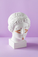 Beige tapes for the face on the bust on a purple background. Non-surgical facelift, rejuvenation.