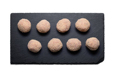 Uncooked meatballs on a slate plate from above with a semitransparent shadow
