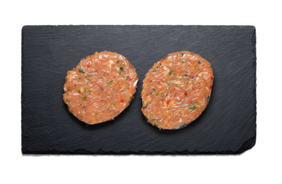 Raw chicken and vegetables burgers on a slate plate from above with a semitransparent shadow