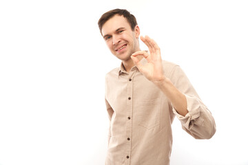 Portrait of young man showing OK sign with fingers isolated on white background. Successful career, approved concept