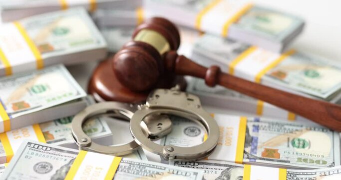 Mallet of judge and handcuff put on packs of dollar bills on table. Judgement on corruption and financial crimes in court. Bribers punishment