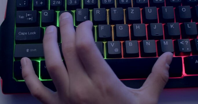 Close-up of using computer keyboard keys. He presses the game control buttons on the character. Motor skills of fingers.