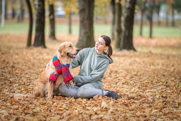 Portrait of a beautiful dark-haired girl with a golden retriever in the autumn park.