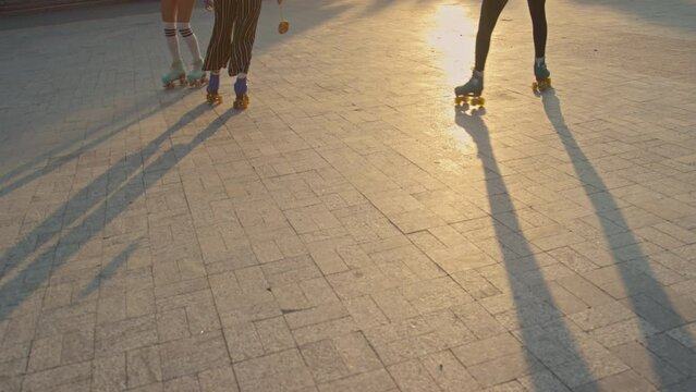 Dutch angle of female legs in colorful vintage quad rollers skating fast outdoor at daytime