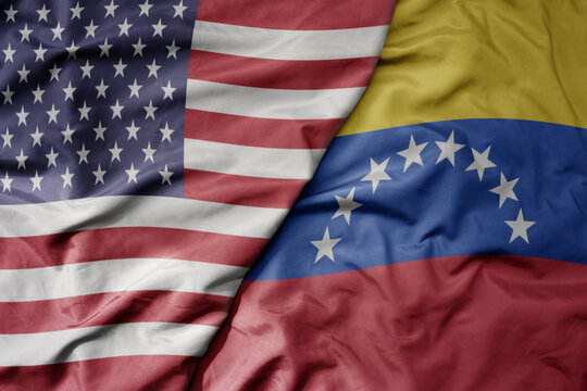 big waving colorful flag of united states of america and national flag of venezuela .