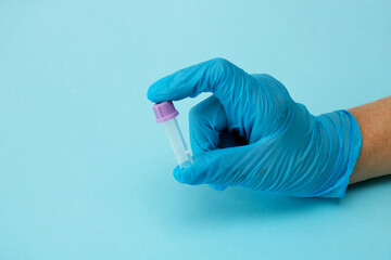 a gloved hand holds an empty test tube on a blue background with copy space, modern diagnostics