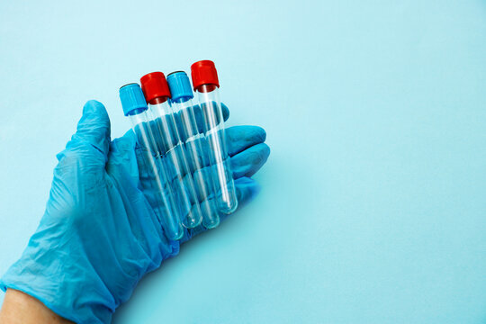 empty test tubes in the hand of a medic in a glove on a blue background