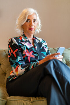 Senior woman sitting on sofa and using smartphone