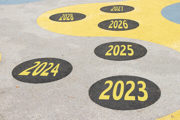 The years from 2023 to 2028 are written on the road in circles on the playground on the floor in...