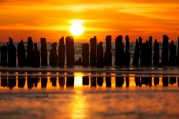 Sunset over the sea, over a wooden breakwater.