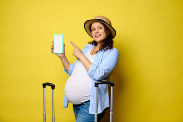 Happy smiling pregnant woman pointing at copy space, on modern smart mobile phone with white blank digital mockup screen