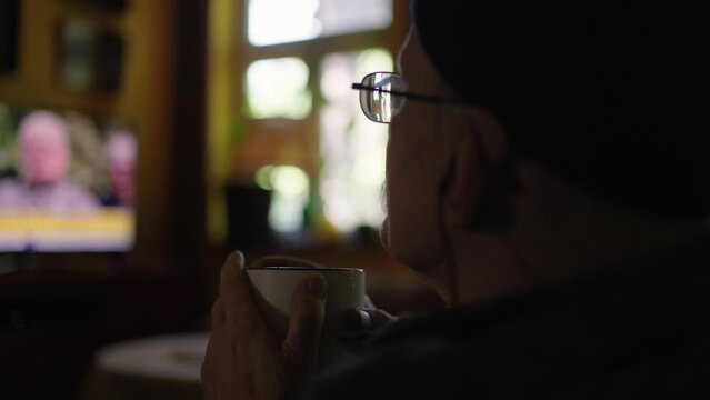 Old man in a wheelchair watching tv in the livingroom at home