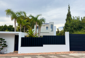 Villa in Los Monasterios Urbanization residential area. Design house and luxury facilities. Fence at a suburb house. Construction of modern house near coastline. Villa under construction in mountains