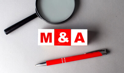 M and A word on wooden cubes with pen and magnifier