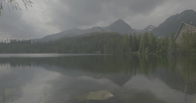 In the mountains, films portray serene lakes. The overcast sky casts a moody atmosphere. Reflections ripple, adding an ethereal charm to the scene. Nature's beauty shines, undeterred by the clouds.