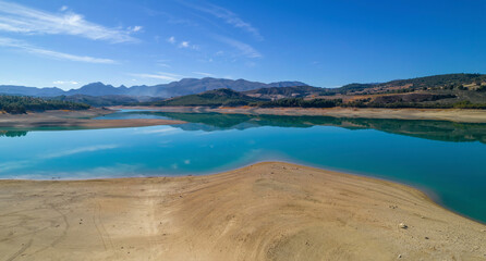 Reservoir photography with reflections in calm water of the sky and mountains Mirror effect of reservoir waters on a calm windy day. Contrasts of color and textures relax Granada Andalusia Spain