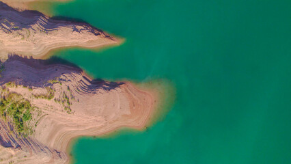 Textures and colors shore next to the reservoir. Aerial photography. Colorful water.