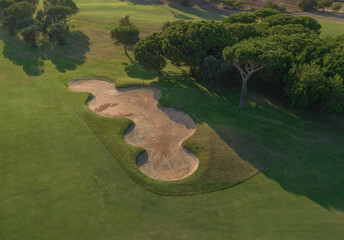 Fairway and sand bunker on golf course at sunset. Spain. Aerial view.