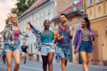 Multiracial group of cheerful friends walking on street while going to summer music festival.