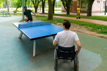Inclusiveness A disabled man in a wheelchair plays ping pong against an old man with a gray beard...