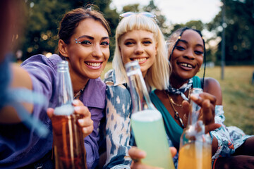 Multiracial group of happy female friends taking selfie during summer music festival.